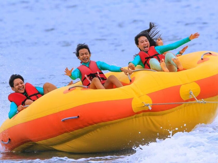 People do the Donut Boat on the calm blue water of Tanjung Benoa beach in Bali.