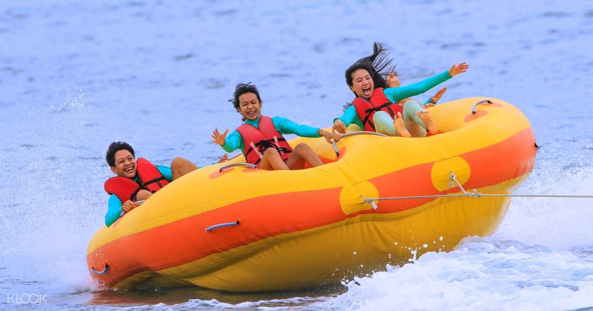 People do the Donut Boat on the calm blue water of Tanjung Benoa beach in Bali.