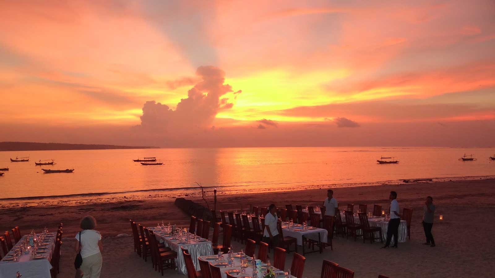 A candlelit seafood dinner platter served on the sand with a sunset view at Jimbaran Bay.