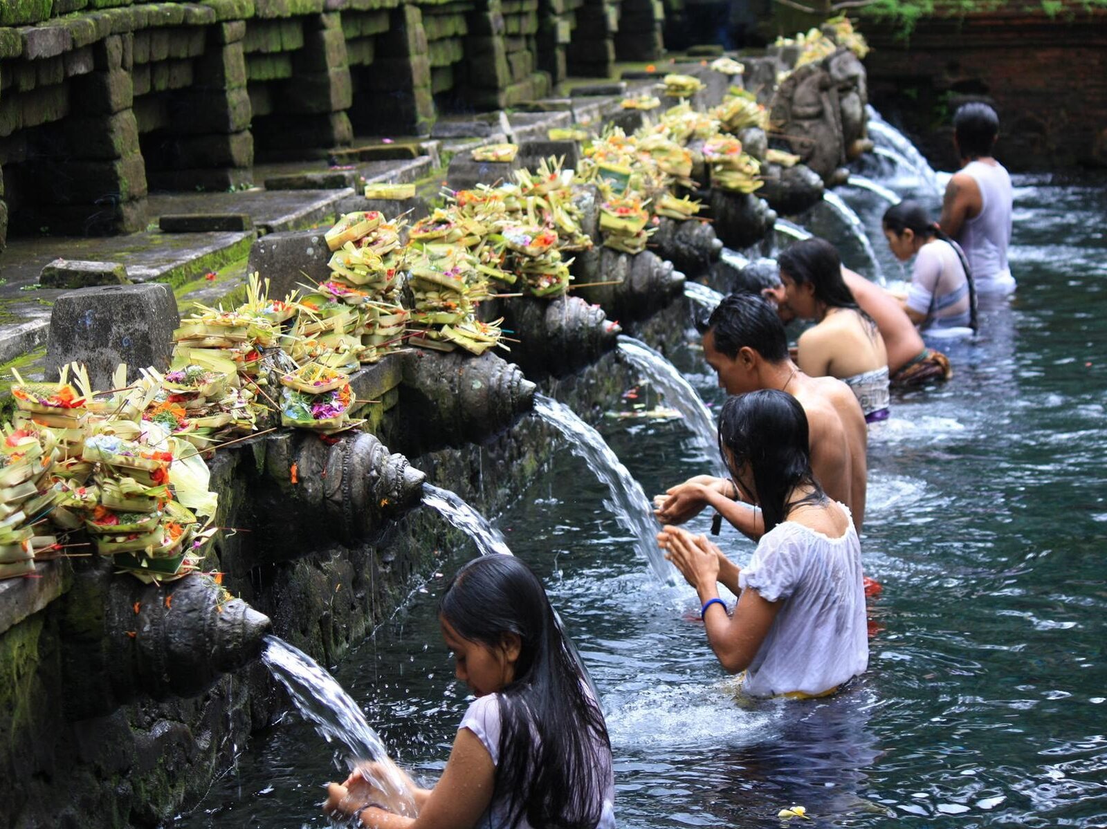 Visitors and locals performing the Melukat purification ritual in the holy spring water pools at Tirta Empul Temple