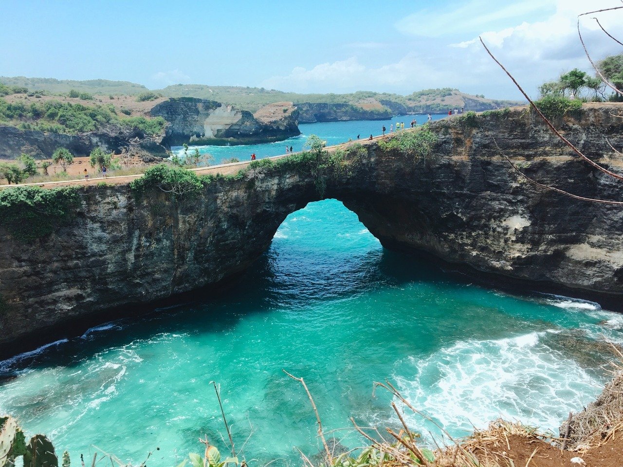 Natural limestone bridge over a circular ocean cove at Broken Beach Nusa Penida.