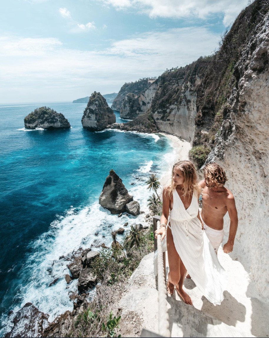 A white staircase carved into a limestone cliff leading down to Diamond Beach Bali.