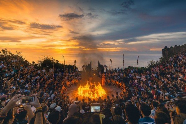 Kecak dance with a sunset over the Indian Ocean behind the perched cliff-edge Uluwatu Temple in Bali.