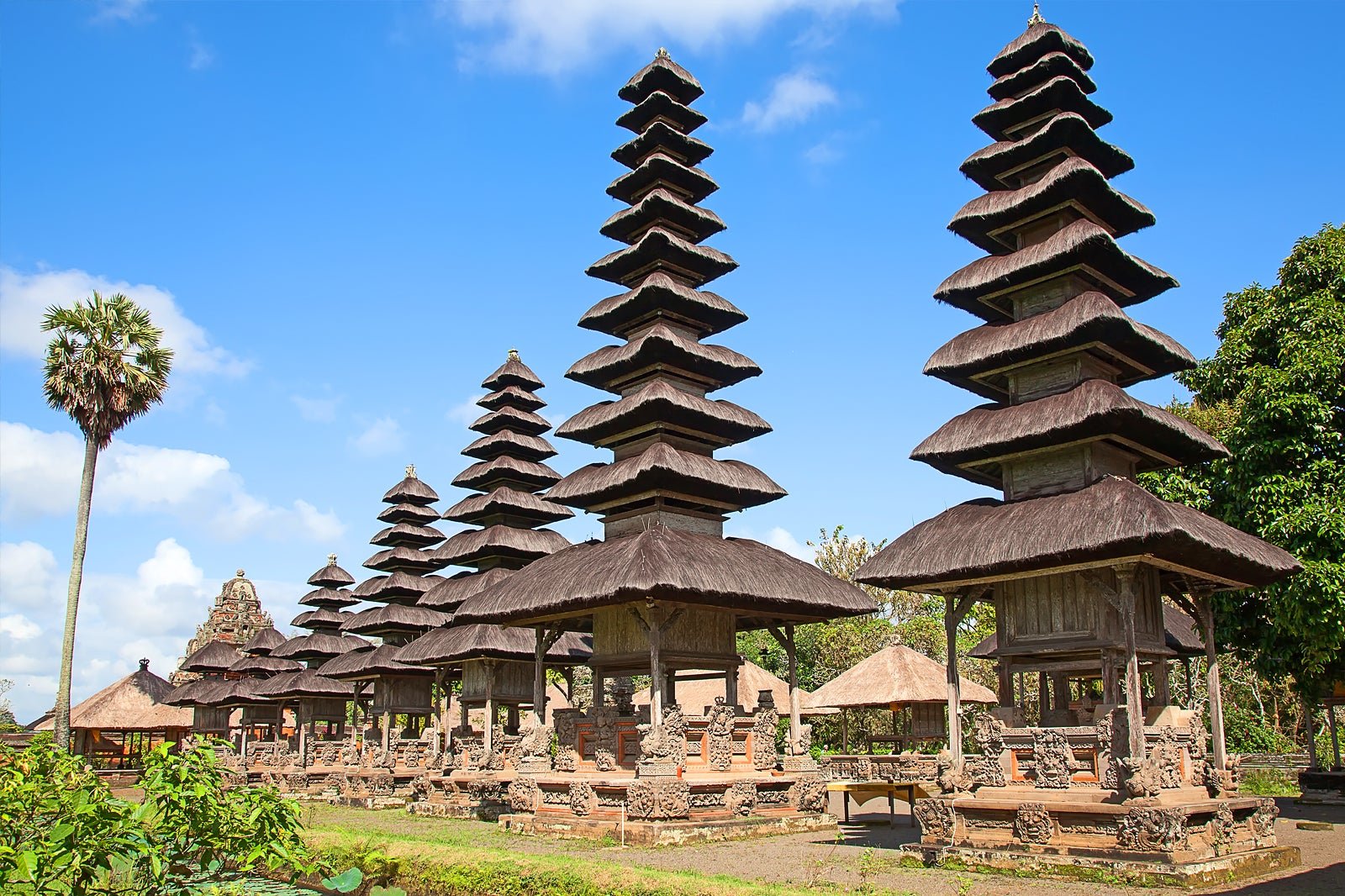 Historic meru towers of the royal Taman Ayun Temple surrounded by calm water and gardens in Bali.