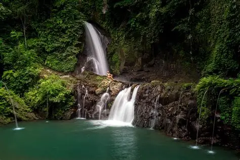 A peaceful, hidden waterfall in a bamboo forest with calm pools at Taman Sari Waterfall, Bali.