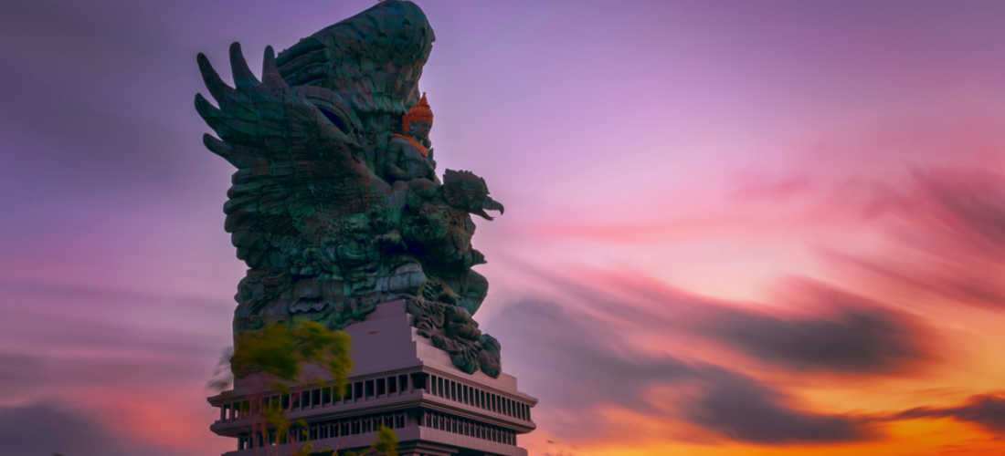 A colossal, 122-meter-tall statue of Garuda Wisnu Kencana against sunset in Bali.